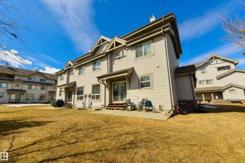 The property features an extensive yard with a lawn, a patio, and a light-colored siding exterior - 67 12050 17 Avenue, Edmonton, AB - Outdoor