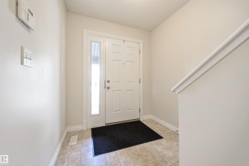 The property features an entryway with tiled flooring and a white front door with a sidelight, providing natural light - 67 12050 17 Avenue, Edmonton, AB - Indoor Photo Showing Other Room
