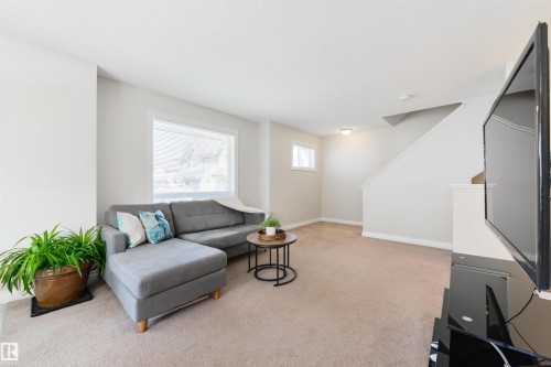 Living area featuring light colored walls, a window with a white frame, and carpeted flooring - 67 12050 17 Avenue, Edmonton, AB - Indoor