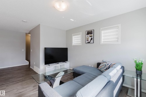 Living space featuring light gray walls, dark wood-style flooring, and a ceiling light fixture - 17268 9B Avenue, Edmonton, AB 