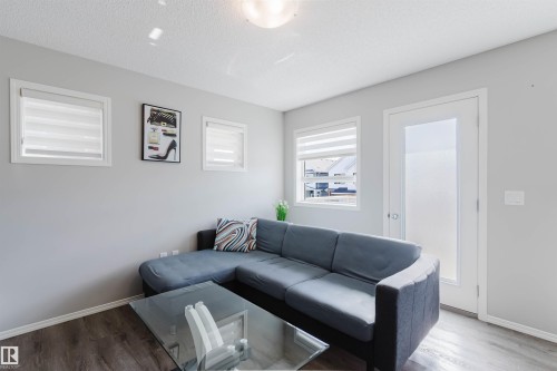 Living area featuring hardwood style flooring, a neutral wall color, and a white door with a frosted glass panel - 17268 9B Avenue, Edmonton, AB 