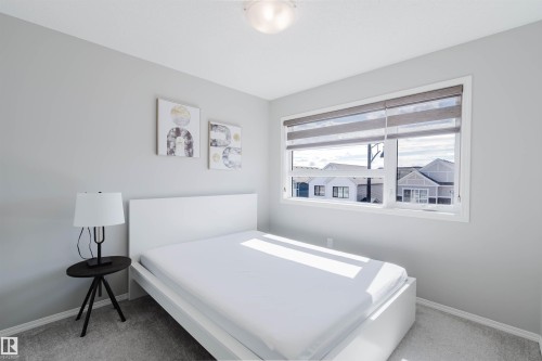 This room features light grey walls, grey carpet flooring, and a window with blinds - 17268 9B Avenue, Edmonton, AB 
