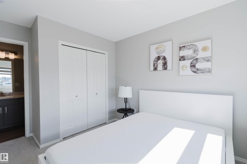 This room features light grey walls, carpeted flooring, and a closet with bi-fold doors - 17268 9B Avenue, Edmonton, AB 