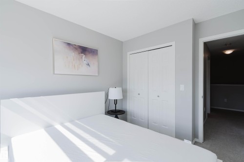 The room features light gray walls, a white bed frame, and white bi-fold closet doors, providing a bright and airy feel - 17268 9B Avenue, Edmonton, AB 