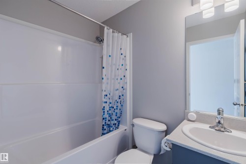 Bathroom featuring a bathtub with shower, a toilet, and a vanity with a sink and mirror - 17268 9B Avenue, Edmonton, AB 