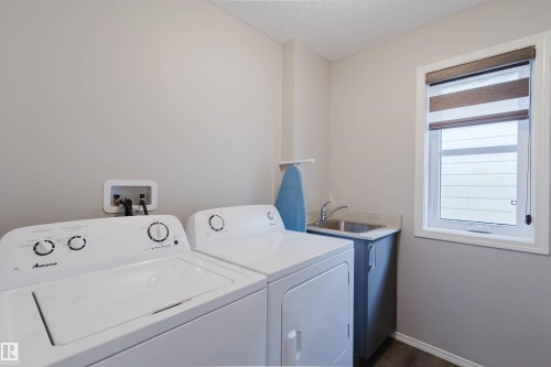 Dedicated laundry area featuring a window, a utility sink with a cabinet, and a washer and dryer - 17268 9B Avenue, Edmonton, AB 