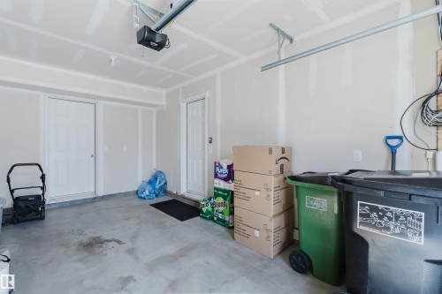 The property features a garage with a concrete floor, two white doors, and an overhead garage door opener mechanism - 17268 9B Avenue, Edmonton, AB 