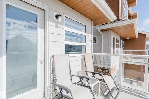 Balcony featuring glass railings, a white exterior door, and horizontal windows - 17268 9B Avenue, Edmonton, AB 