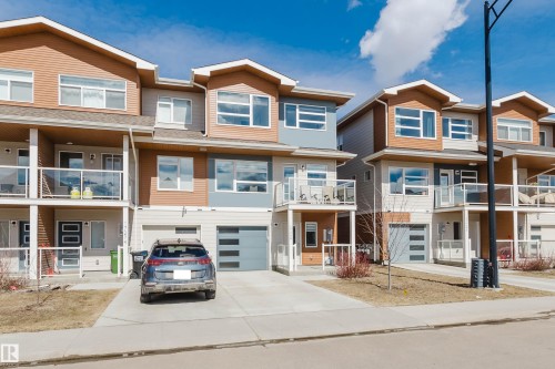 The property features a contemporary exterior with multi-toned siding, a private balcony with a glass railing, and an integrated garage with a modern style door - 17268 9B Avenue, Edmonton, AB 