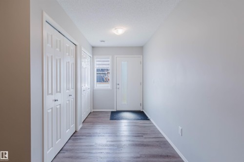 Entryway featuring wood-look flooring, white walls, and a front door with an opaque glass insert - 17268 9B Avenue, Edmonton, AB 
