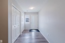 Entryway featuring wood-look flooring, white walls, and a front door with an opaque glass insert - 17268 9B Avenue, Edmonton, AB 