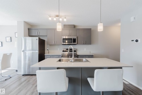 Kitchen featuring grey cabinetry, stainless steel appliances, a white island with an undermount sink, and pendant lighting - 17268 9B Avenue, Edmonton, AB 