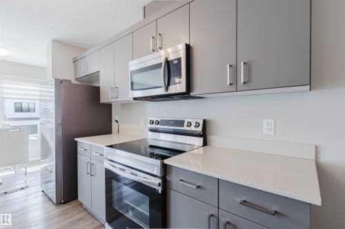 The kitchen features grey cabinetry, stainless steel appliances, and light-colored countertops - 17268 9B Avenue, Edmonton, AB 