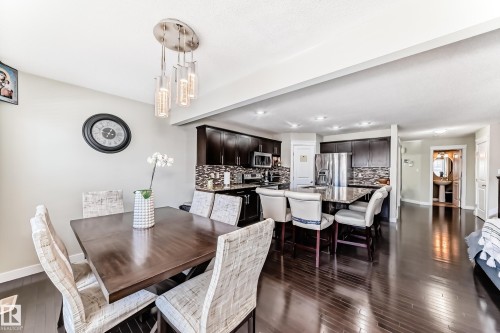 Open concept dining area and kitchen featuring dark hardwood floors, recessed lighting, and a modern chandelier - 3433 Goodridge Link Link, Edmonton, AB - Indoor Photo Showing Dining Room