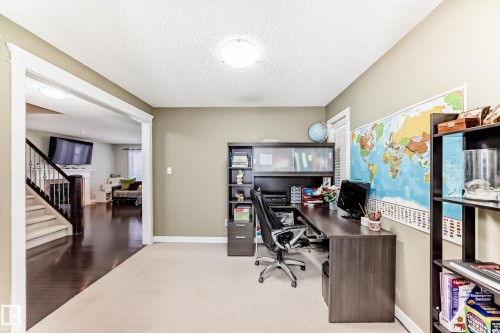 This dedicated office space features light-colored carpeting, a wall-mounted world map, and a ceiling light fixture - 3433 Goodridge Link Link, Edmonton, AB - Indoor Photo Showing Office