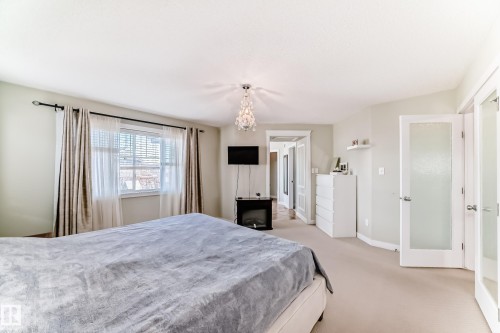 The room features a window with blinds and curtains, a decorative ceiling light fixture, and carpeted floors - 3433 Goodridge Link Link, Edmonton, AB - Indoor Photo Showing Bedroom