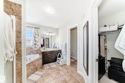 The bathroom features a built-in bathtub, a window with drapery, and a vanity with a mirror and overhead lighting - 3433 Goodridge Link Link, Edmonton, AB - Indoor Photo Showing Bathroom