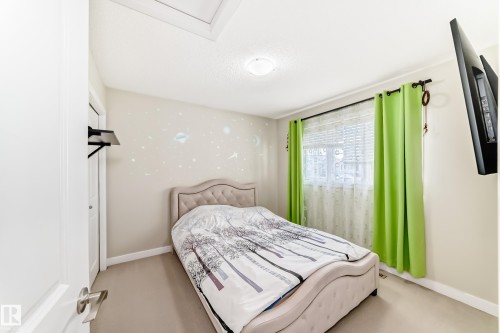 Bedroom featuring a window with blinds and curtains, a ceiling light fixture, and light-colored carpeting - 3433 Goodridge Link Link, Edmonton, AB - Indoor Photo Showing Bedroom