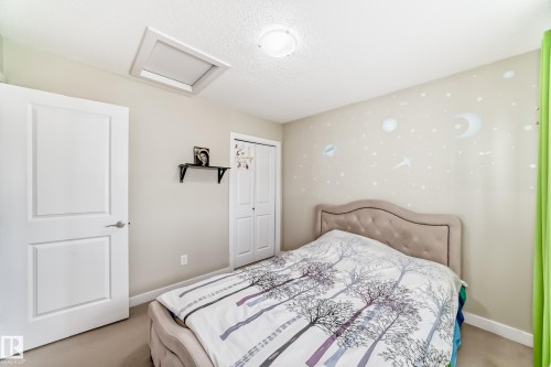 Bedroom featuring a light-colored carpet, white doors, and a skylight for natural illumination - 3433 Goodridge Link Link, Edmonton, AB - Indoor Photo Showing Bedroom