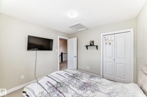 This room features light-colored walls and carpet flooring, a white ceiling with a flush-mount light fixture, and a white bi-fold closet door - 3433 Goodridge Link Link, Edmonton, AB - Indoor Photo Showing Bedroom