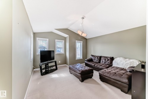 This living area features a vaulted ceiling, neutral-toned walls, and carpeted flooring - 3433 Goodridge Link Link, Edmonton, AB - Indoor