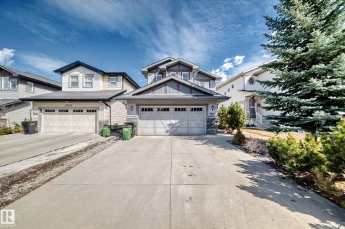 The property features a two-story exterior with a blend of siding and stone accents, a double garage, and a concrete driveway - 3433 Goodridge Link Link, Edmonton, AB - Outdoor With Facade