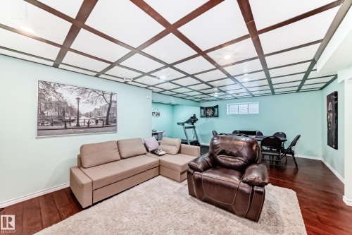 Spacious room featuring a decorative coffered ceiling, light green walls, and dark wood flooring - 3433 Goodridge Link Link, Edmonton, AB - Indoor