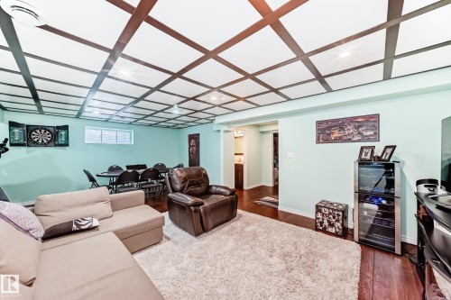 The living space features a coffered ceiling, light green walls, and rich hardwood flooring - 3433 Goodridge Link Link, Edmonton, AB - Indoor