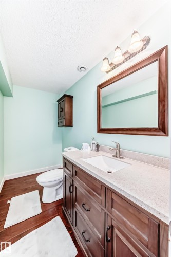 Bathroom featuring a rich wood vanity with a light-colored countertop, an undermount sink, and a framed mirror - 3433 Goodridge Link Link, Edmonton, AB - Indoor Photo Showing Bathroom