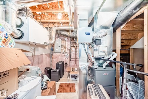 The property includes a basement utility area featuring exposed wood joists, ductwork, and essential mechanical systems - 3433 Goodridge Link Link, Edmonton, AB - Indoor Photo Showing Basement