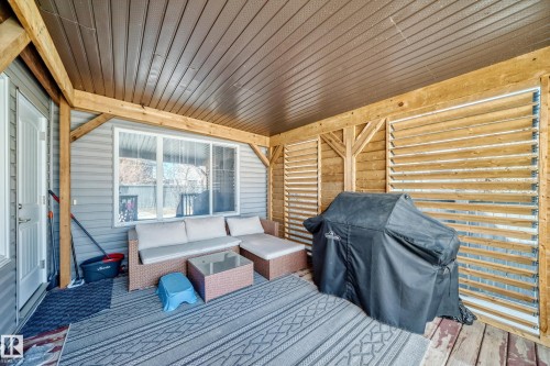 The property features a covered patio with wooden beam supports and slatted wood panels - 3433 Goodridge Link Link, Edmonton, AB - Outdoor With Deck Patio Veranda With Exterior