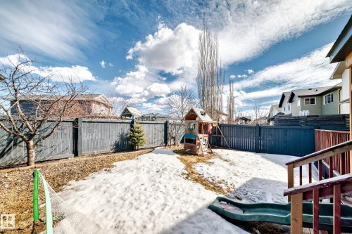 The property features a fenced backyard with a wooden playset and a green slide - 3433 Goodridge Link Link, Edmonton, AB - Outdoor