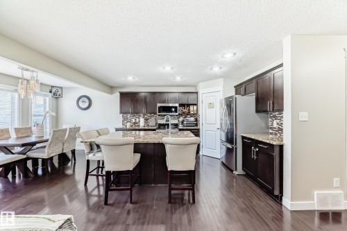 Open concept kitchen and dining area featuring dark wood flooring, recessed lighting, and a kitchen island with seating - 3433 Goodridge Link Link, Edmonton, AB - Indoor Photo Showing Dining Room