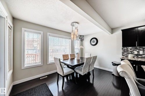 Dining area featuring dark hardwood floors, a modern chandelier, and light-colored walls - 3433 Goodridge Link Link, Edmonton, AB - Indoor Photo Showing Dining Room