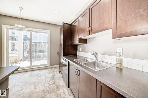 Kitchen featuring wood cabinetry, a stainless steel double basin sink, and white subway tile backsplash - 44 13825 155 Avenue, Edmonton, AB - Indoor Photo Showing Kitchen With Double Sink
