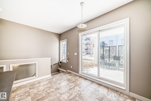 The dining area features tiled flooring, a modern light fixture, and sliding glass doors that open to an outdoor patio area - 44 13825 155 Avenue, Edmonton, AB - Indoor Photo Showing Other Room