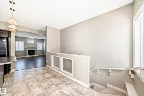 The property features a spacious interior with tiled flooring in the foreground, transitioning to dark wood flooring in the background - 44 13825 155 Avenue, Edmonton, AB - Indoor Photo Showing Other Room With Fireplace