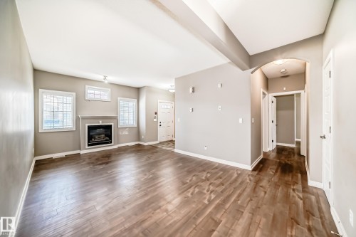 The living area features hardwood floors, a gas fireplace, and multiple windows - 44 13825 155 Avenue, Edmonton, AB - Indoor Photo Showing Living Room With Fireplace