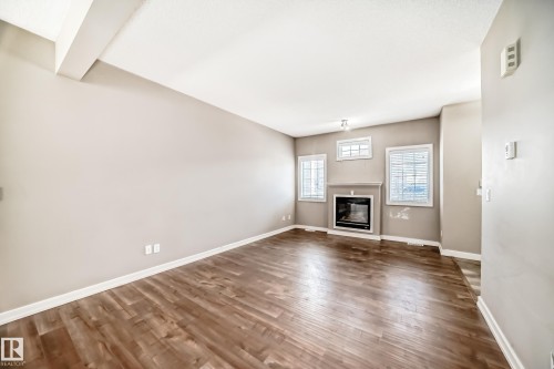 The living area features hardwood floors and a fireplace with a mantel, complemented by light-colored walls and white trim - 44 13825 155 Avenue, Edmonton, AB - Indoor Photo Showing Other Room With Fireplace