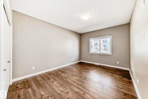 Room with wood-look flooring, neutral-toned walls, a window, and a ceiling light fixture - 44 13825 155 Avenue, Edmonton, AB - Indoor Photo Showing Other Room
