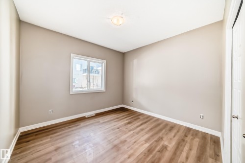 The room features wood-look flooring, neutral-toned walls, and a window providing natural light - 44 13825 155 Avenue, Edmonton, AB - Indoor Photo Showing Other Room
