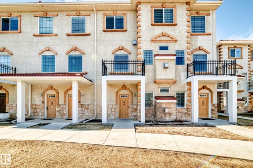 The property features a stucco exterior with stone accents, arched entryways, and decorative window surrounds - 44 13825 155 Avenue, Edmonton, AB - Outdoor With Facade