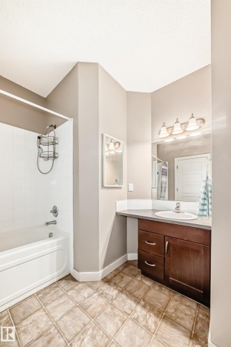 Bathroom featuring a white bathtub with a shower, a vanity with a white sink, and tiled flooring - 44 13825 155 Avenue, Edmonton, AB - Indoor Photo Showing Bathroom