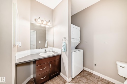 The property features a vanity with a sink, a mirror, and a light fixture, as well as a stacked washer and dryer - 44 13825 155 Avenue, Edmonton, AB - Indoor