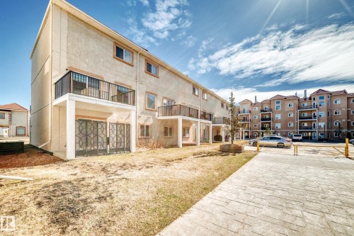 The property features an exterior with balconies and ground level patios, complemented by a paved pathway and a landscaped area - 44 13825 155 Avenue, Edmonton, AB - Outdoor With Deck Patio Veranda