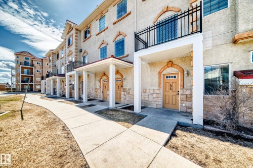 This property features a stucco exterior with decorative stone accents and arched window details - 44 13825 155 Avenue, Edmonton, AB - Outdoor With Facade