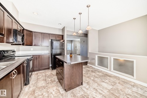Kitchen featuring dark wood cabinetry, a central island, and pendant lighting - 44 13825 155 Avenue, Edmonton, AB - Indoor Photo Showing Kitchen