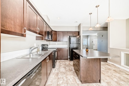 The property features a kitchen with dark wood cabinetry, a stainless steel sink, and a dishwasher - 44 13825 155 Avenue, Edmonton, AB - Indoor Photo Showing Kitchen With Double Sink