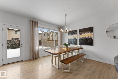 Dining area featuring light-toned flooring, a modern chandelier, and large windows providing natural light - 13 Spring Link, Spruce Grove, AB - Indoor