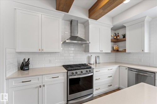 The kitchen features white cabinetry, light-colored countertops, a subway tile backsplash, and stainless steel appliances including a range and dishwasher - 13 Spring Link, Spruce Grove, AB - Indoor Photo Showing Kitchen